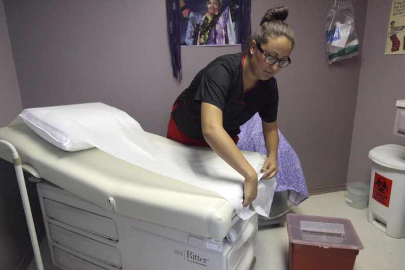Isabela Speedon, a medical assistant, puts clean sheets on an examining table at the Whole...