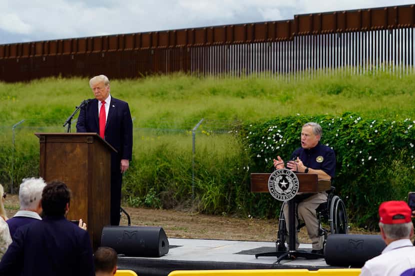 Former President Donald Trump and Texas Gov. Greg Abbott, right, visit an unfinished section...