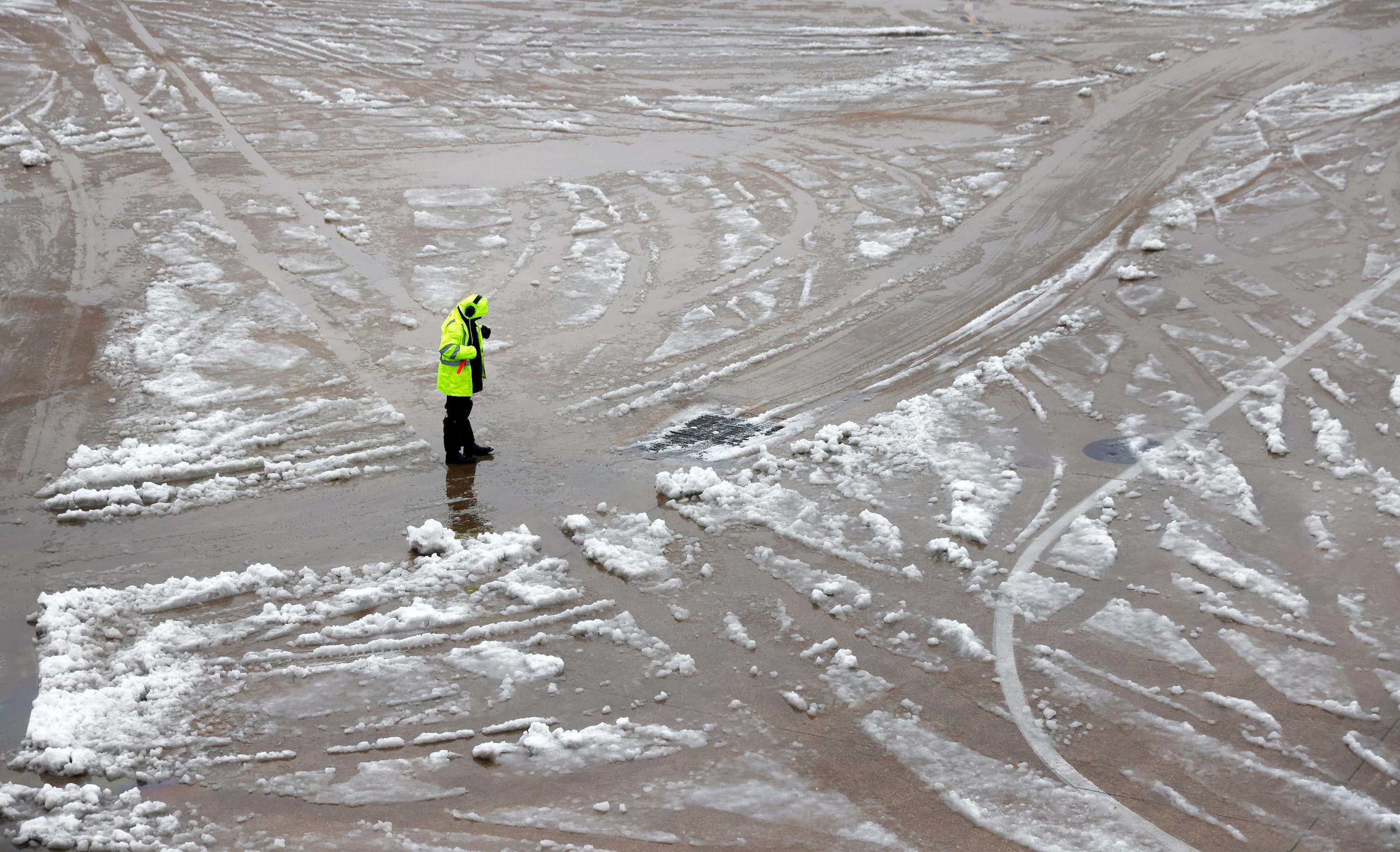 Standing in slush, a grounds crewman waits to guide an American Airlines flight from the...