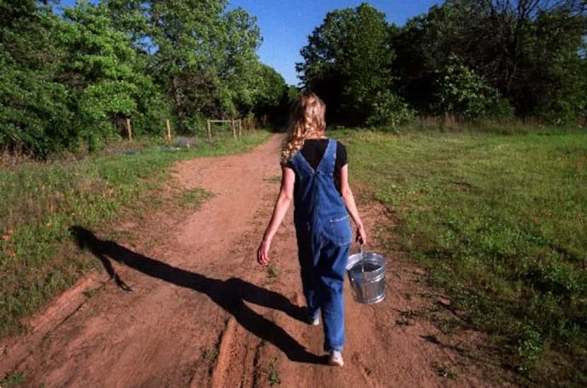 Jeanette Kinman walks down a dirt road to feed the chickens at a spiritual commune called...