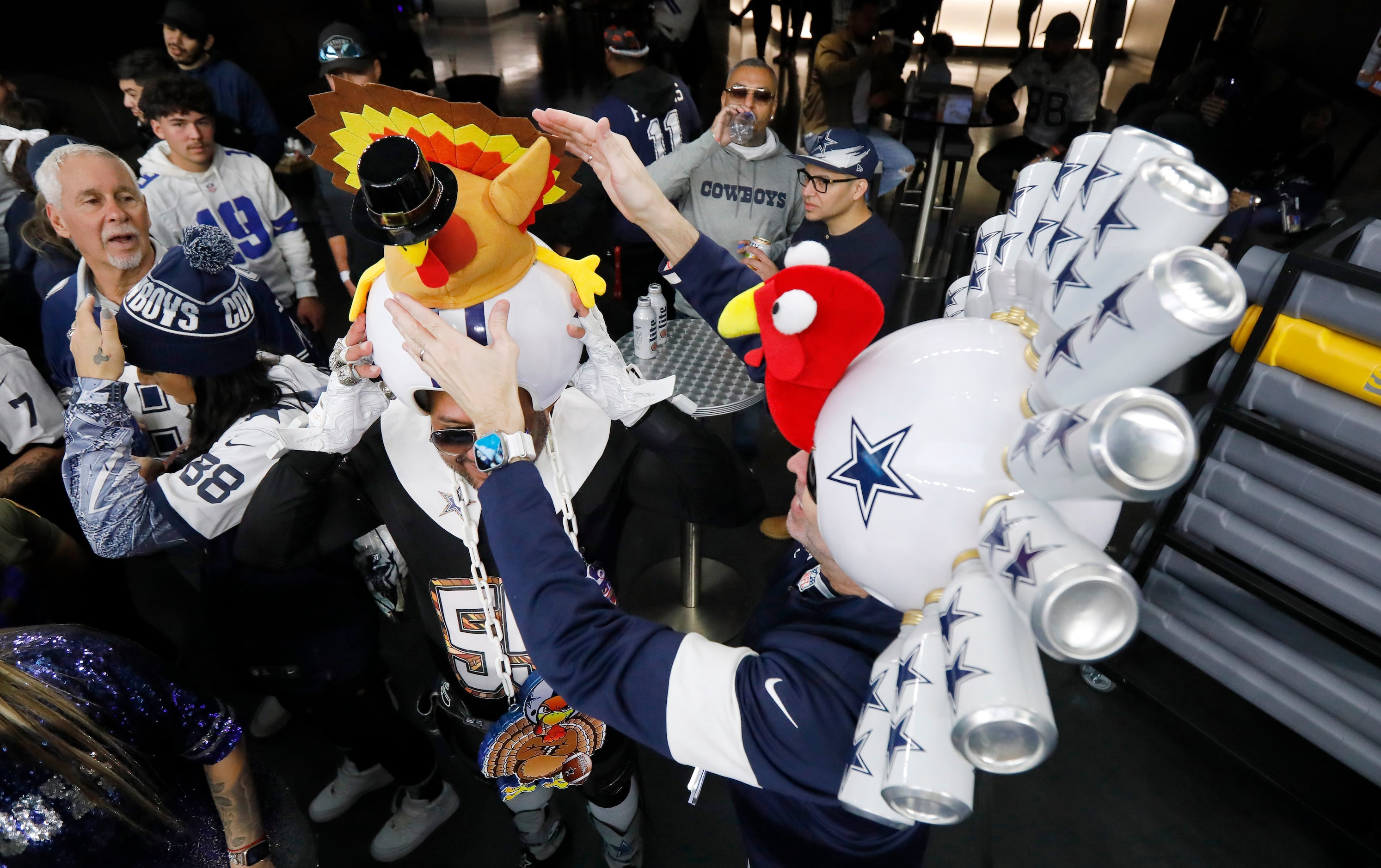 Dallas Cowboys fan Gregg Wilson (right) adjusts the turkey hat on Jaime Castro’s helmet...