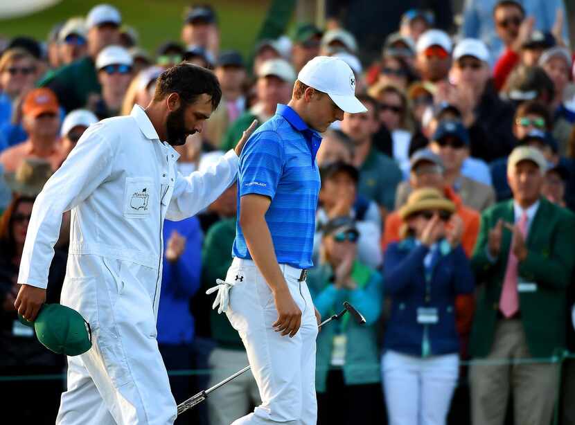 
Caddie Michael Greller, left, pats Jordan Spieth, right, on the back as they exit the 18th...