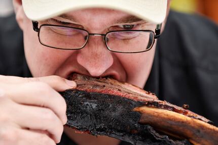 Certified barbeque judge Bruce Lederer of Paris, Texas, bites into beef rib at the Dallas...