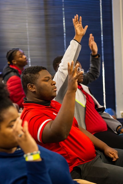 Students hold up their hands to ask questions.