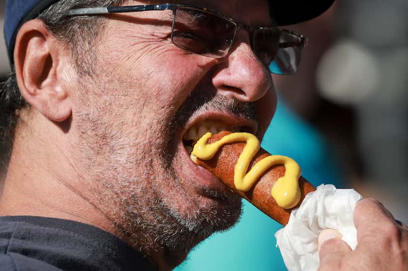 Nick Londakos takes a bite of his Fletcher’s Corny Dog, Friday, Oct. 14, 2022 at the State...