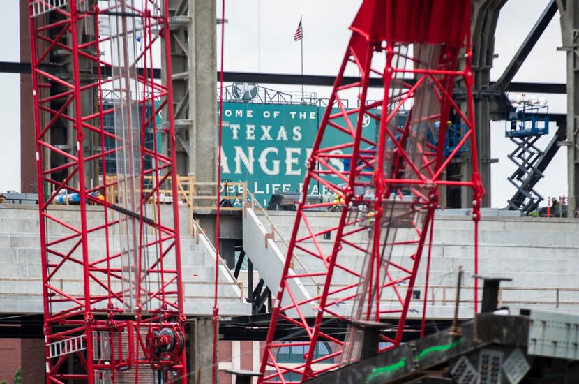 A "Home of the Rangers" sign at Globe Life Park is seen through construction cranes at Globe...