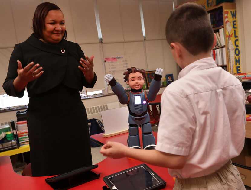 Karol Henderson (izq.) y Maxwell Cowles bailan con Milo, el robot interactivo en la primaria...