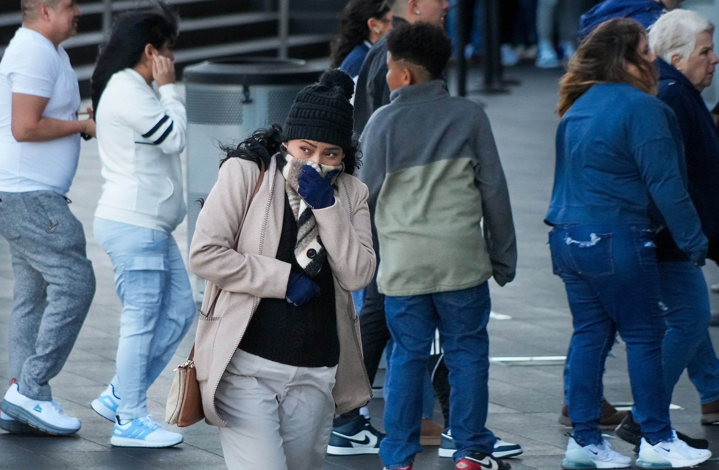 Fans brace from a cold wind as they wait for the gates to open before an NFL football game...