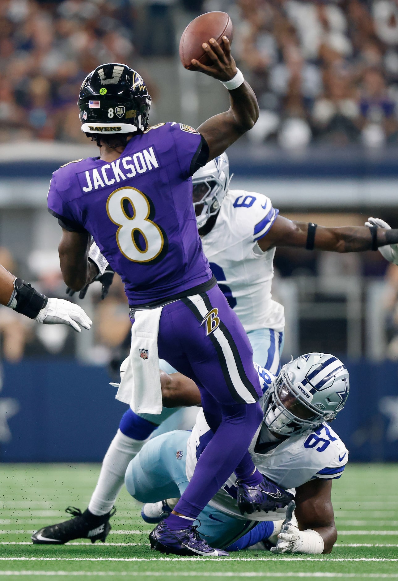 Baltimore Ravens quarterback Lamar Jackson (8) releases a pass as he’s grabbed by Dallas...