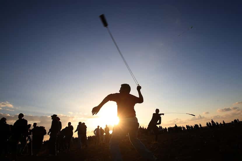Palestinian protesters use slingshots to hurl stones during a demonstration near the border...