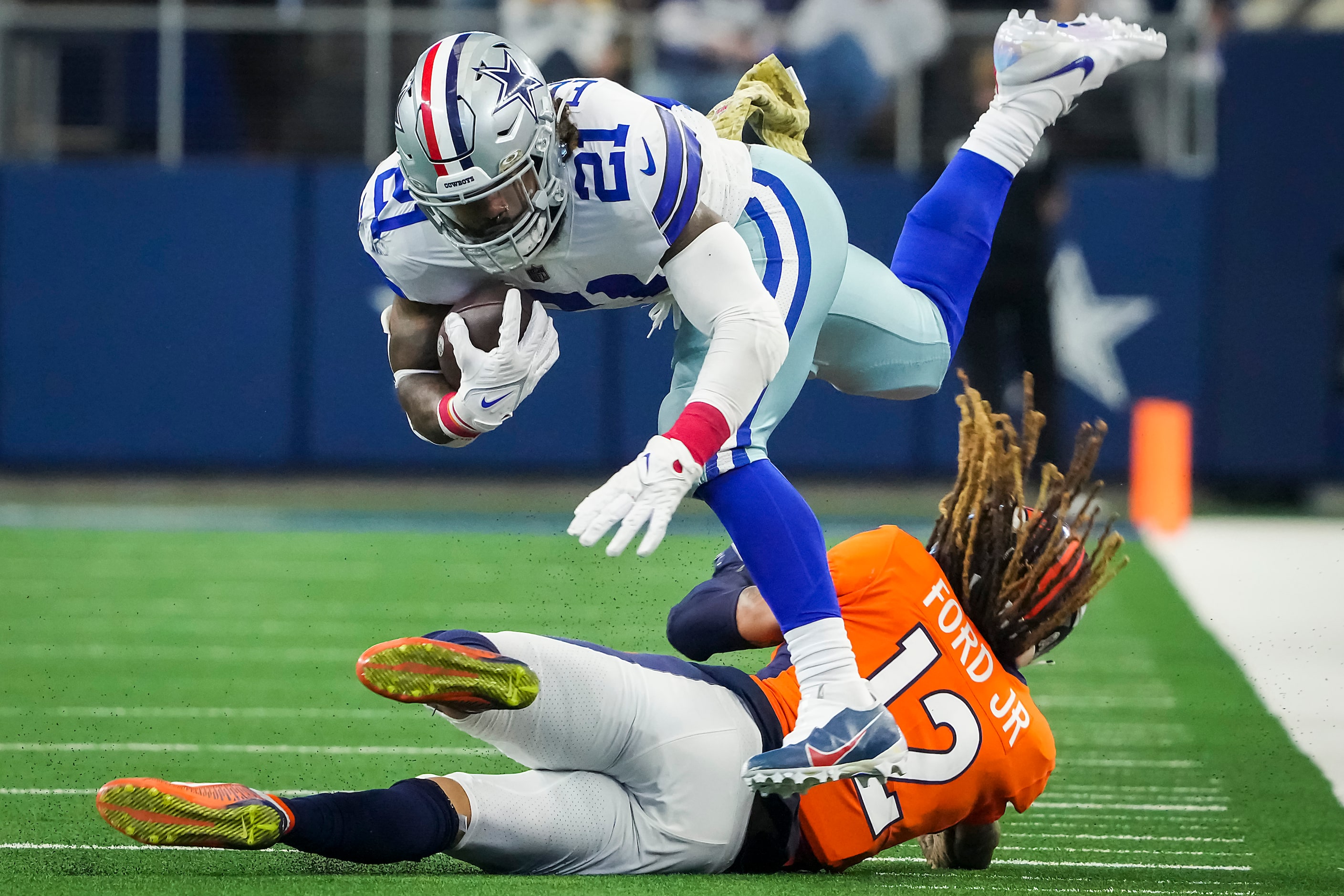 Dallas Cowboys running back Ezekiel Elliott (21) is knocked off his feet by Denver Broncos...