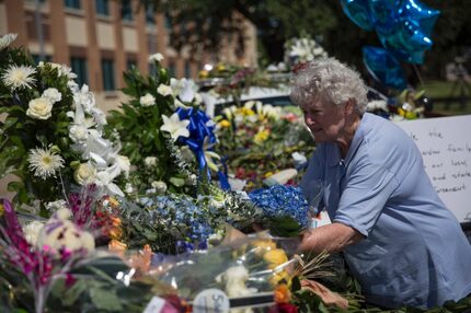 A woman places flowers at a memorial outside the Dallas police headquarters.   