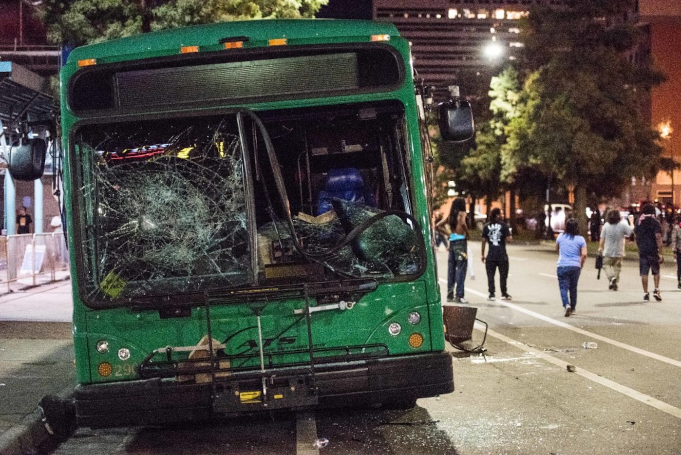 CHARLOTTE, NC - SEPTEMBER 22: Demonstrators walk near a damaged bus on September 22, 2016 in...