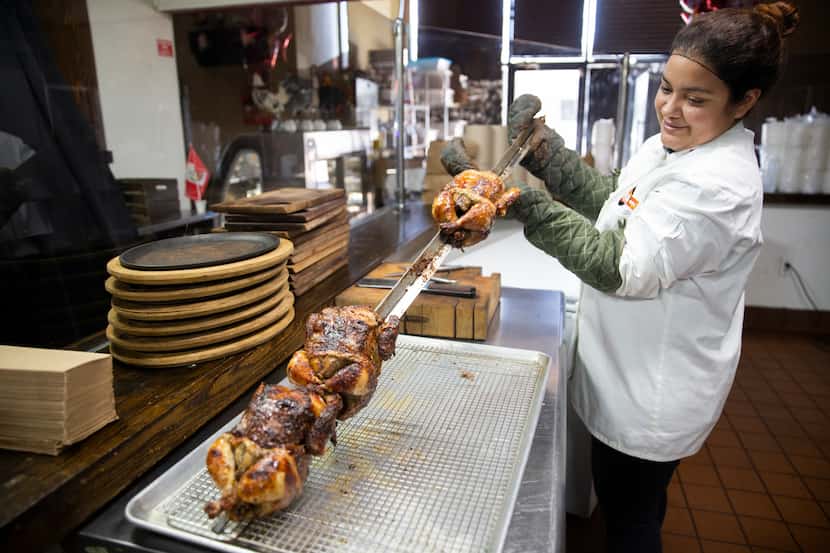 Jenny Lopez takes the pollo a la brasa (Peruvian roasted chicken) out of the oven at the...