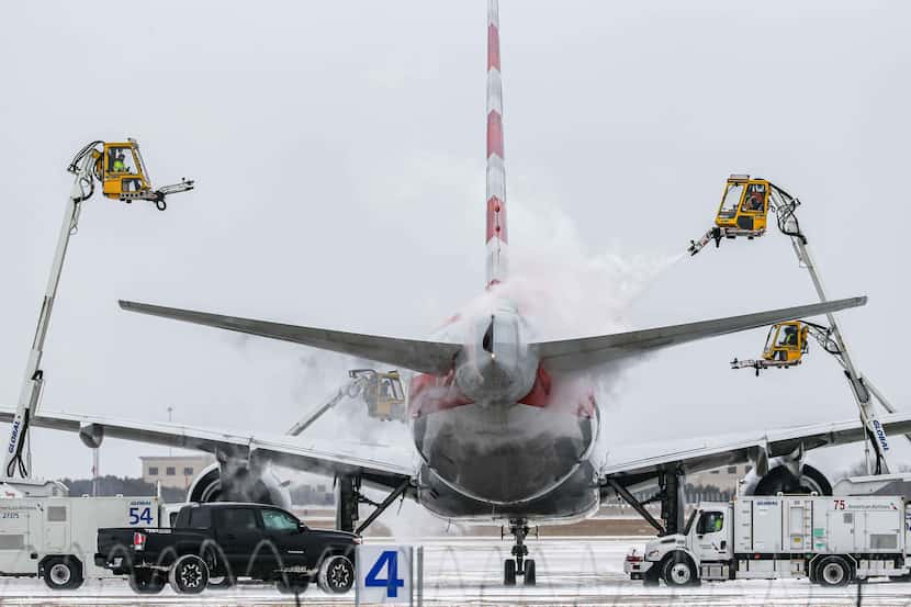 An American Airlines jet is de-iced at DFW International Airport before takeoff as winter...