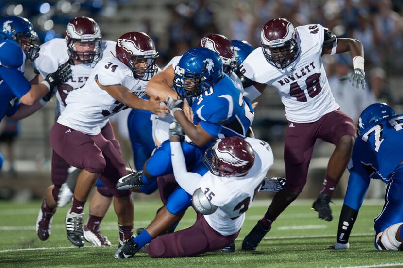 North Mesquite running back Corey Hunt is brought down by a trio of Rowlett defenders during...
