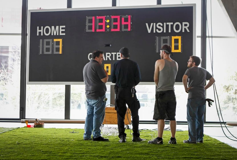 
Dallas Theater Center’s Matthew McKinney (left) discusses the scoreboard installation with...