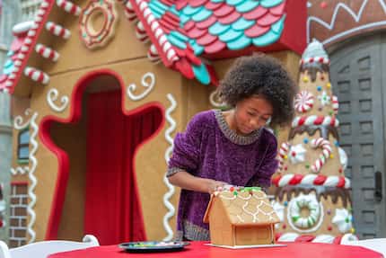 A guest decorates a festive house at the Gingerbread Decorating Corner.