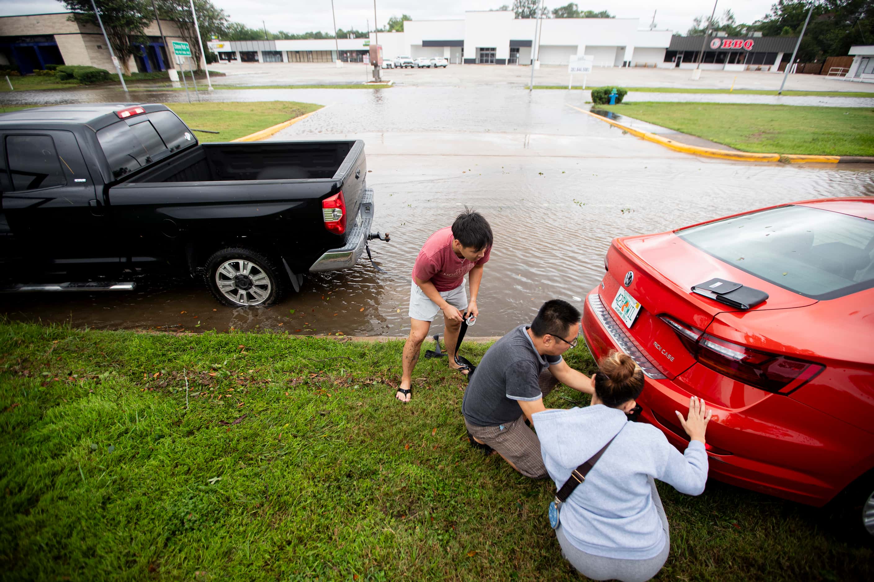Anthony Le, left, and his father Phuong Le help pull a car stuck in the mud after Beryl made...