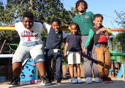 Five school-aged African American boys in school uniforms and casual clothes pose at a...