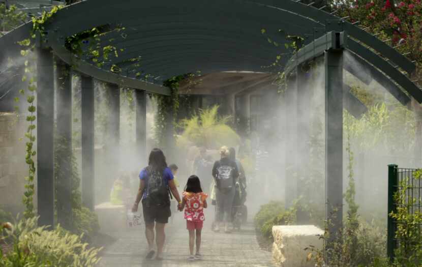 Patrons walk through water misters at the new Rory Meyers Children's Adventure Garden at the...
