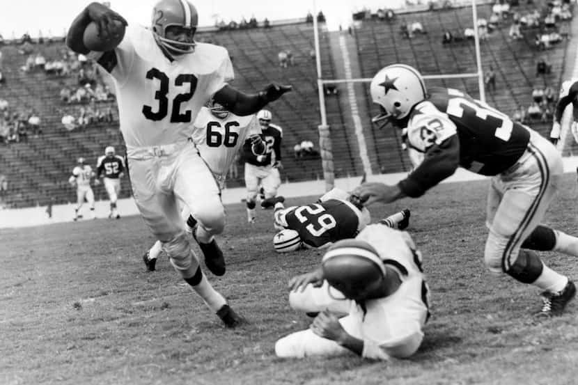 Jim Brown (32), fullback of the Cleveland Browns, rounds at right end after receiving a pass...