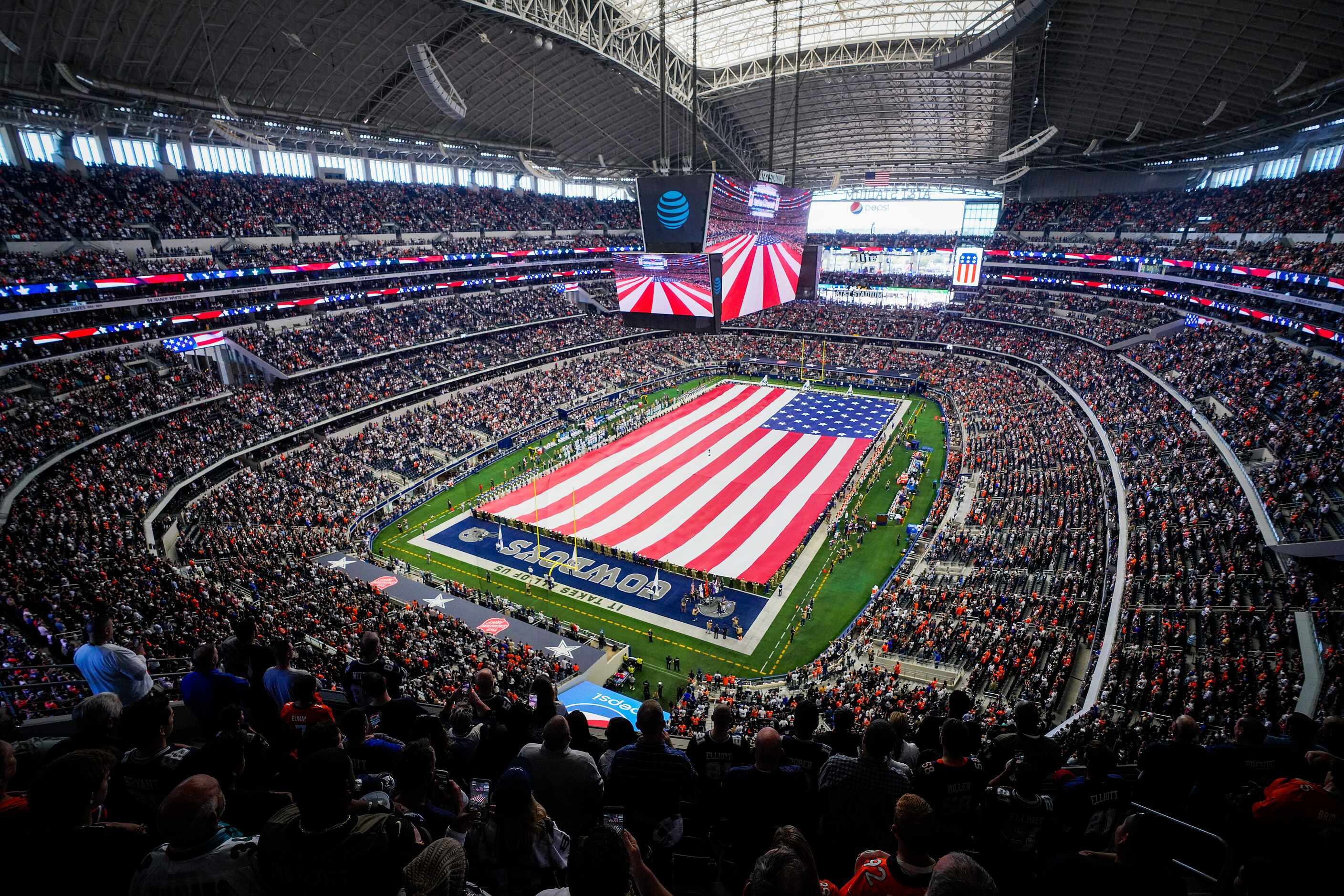 The American flag covers the field during the playing of the national anthem before an NFL...