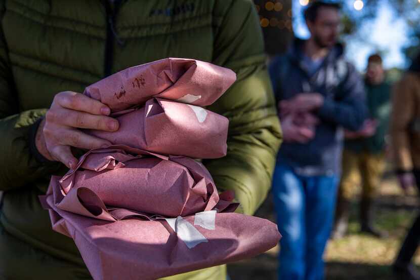 Attendees leave with cuts of meat from bison 26 after a daylong bison field harvest event at...
