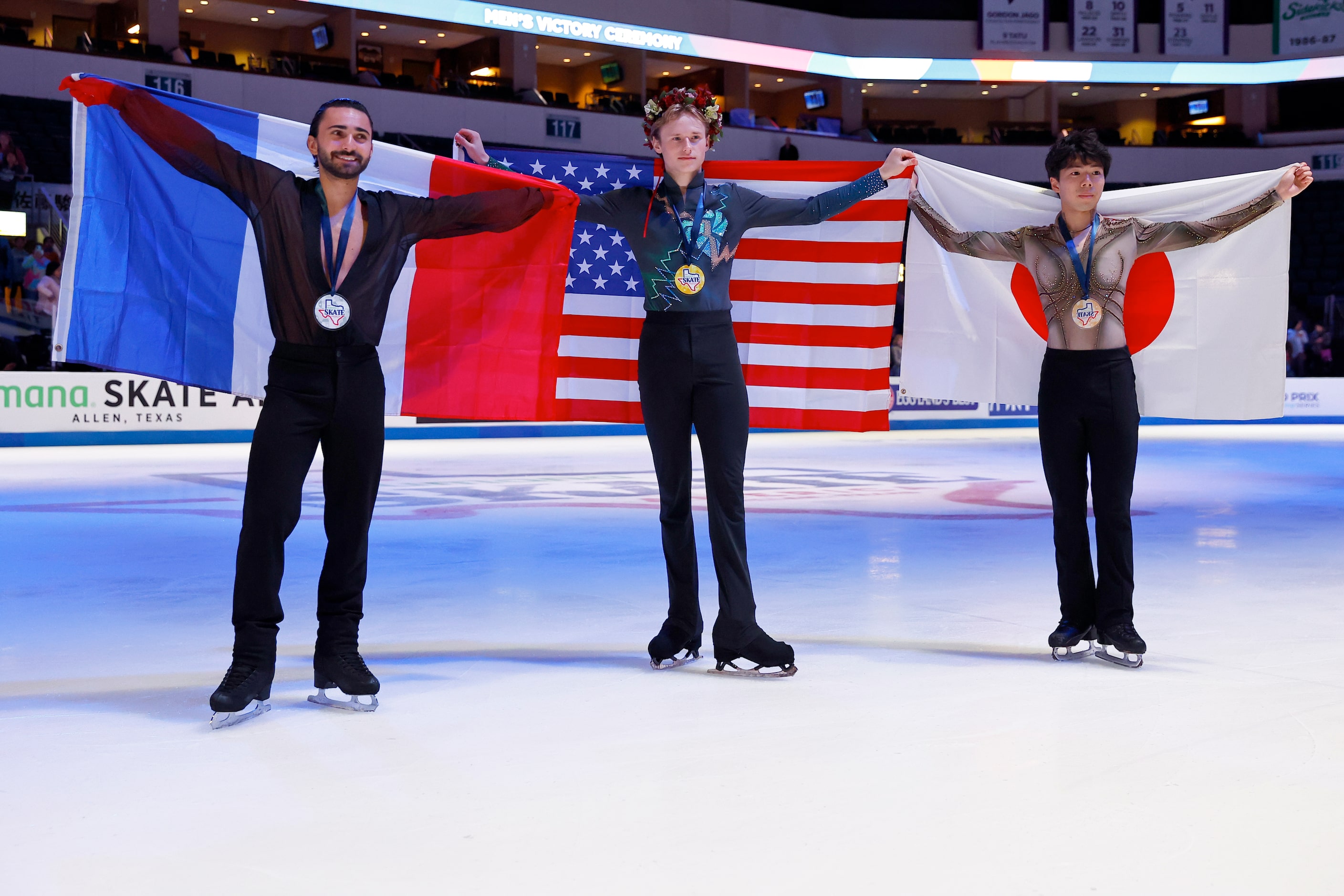 Ilia Malinin, of the United States, center, poses for photos after winning the gold medal in...