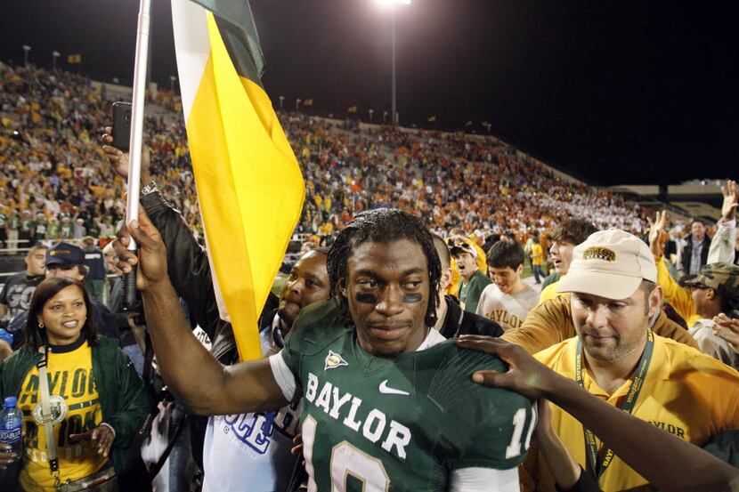 Baylor Bears quarterback Robert Griffin III (10) carries a flag as fans and teammates gather...