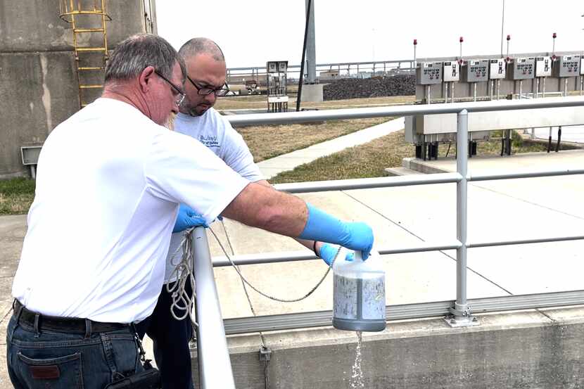 Larry Middleton, front, operations supervisor of Central Wastewater Treatment Plant, pours...