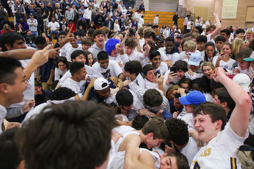 The St. Mark's student section dog pile the players after winning a SPC boys basketball...