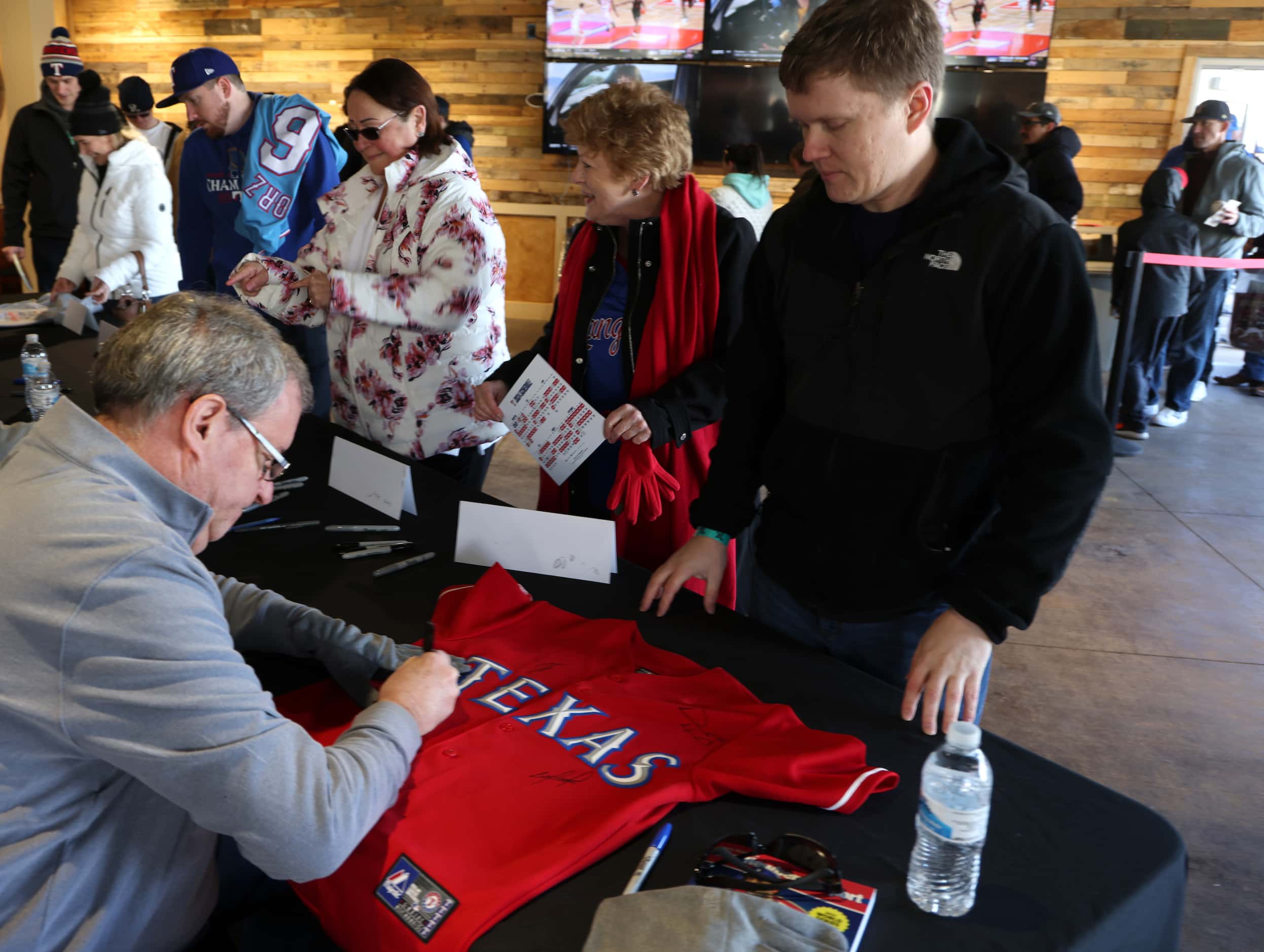 Texas Rangers fan Dan Marchioli looks on as Rangers radio announcer Matt Hicks autographs...