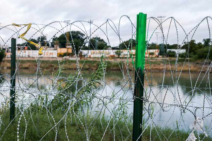 Barbed wire stretches along the Rio Grande on the United States side of the border to...