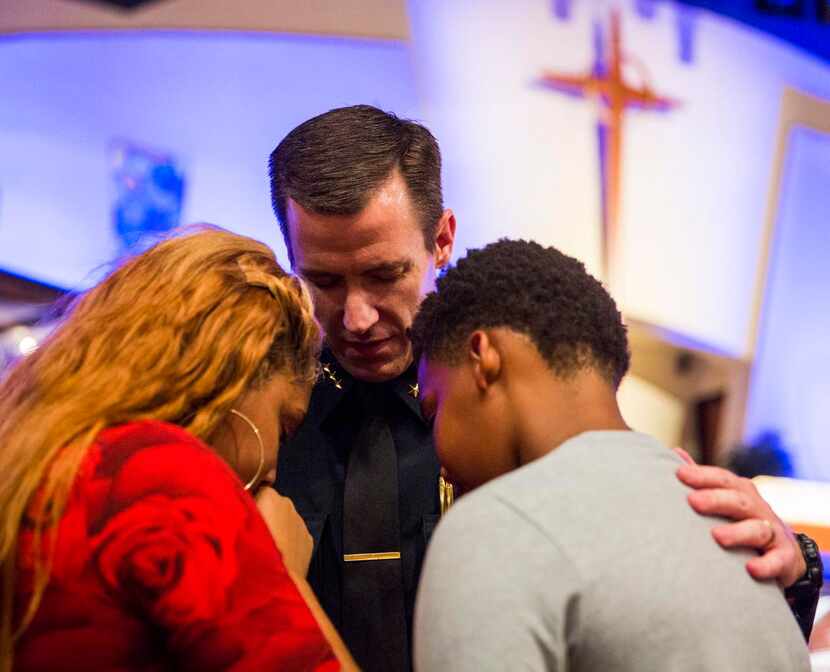
Arlington Police Chief Will Johnson, center, prays with Hannah Jordan, 15, left, and Josiah...