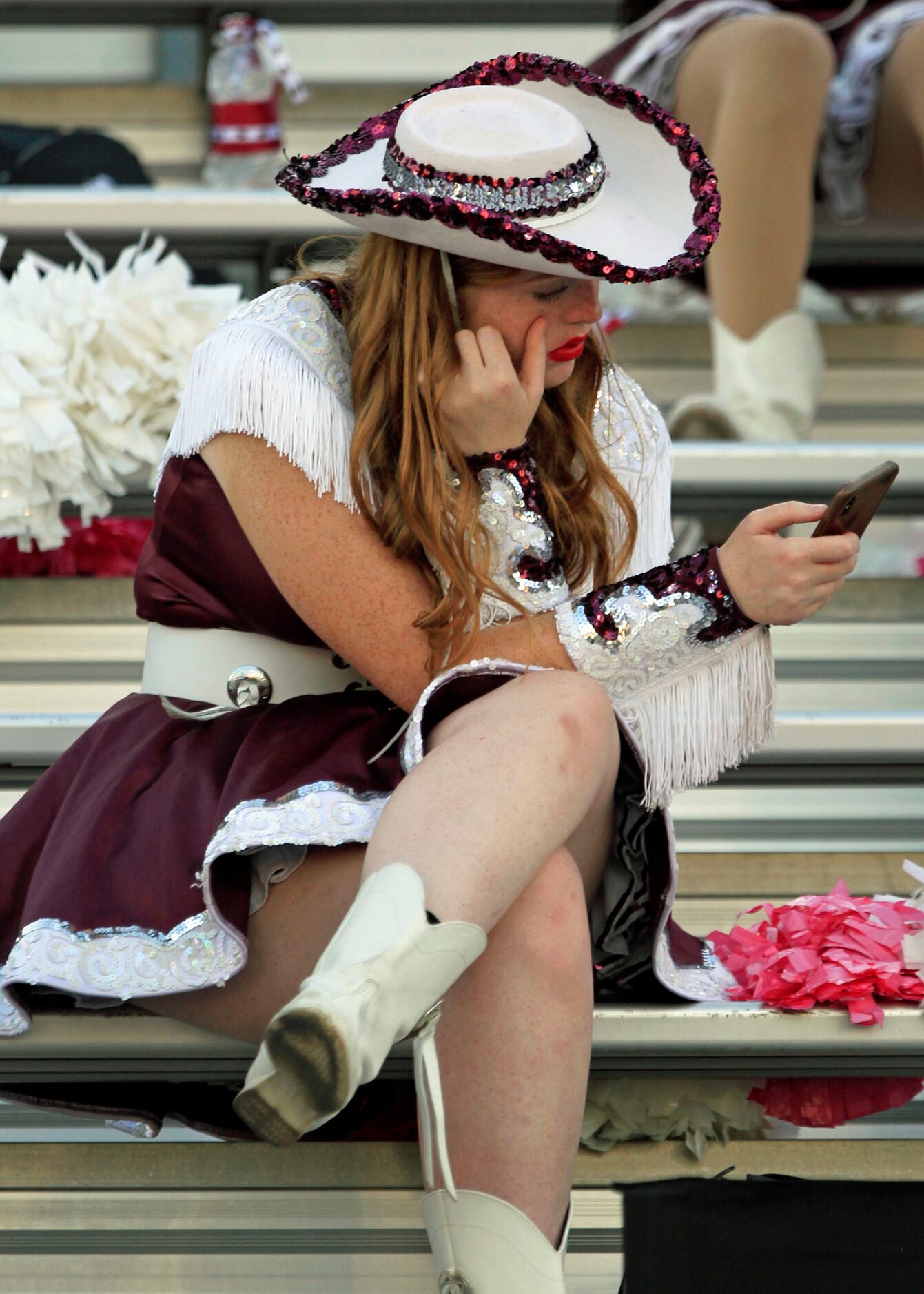A Mesquite High drill team member reads her smartphone before the start of a high school...