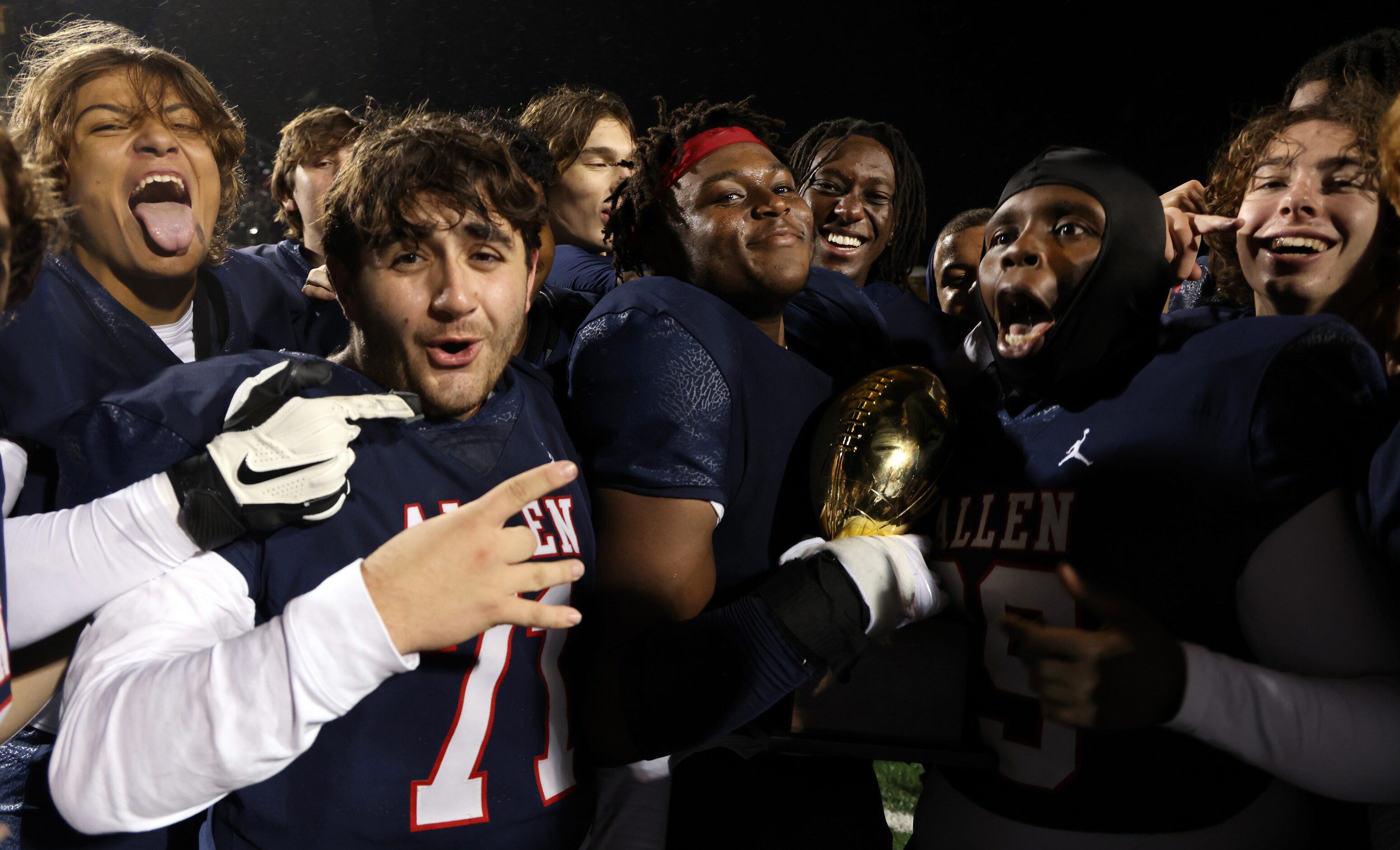 Allen players revel in the moment after being awarded the Bi-District trophy following their...