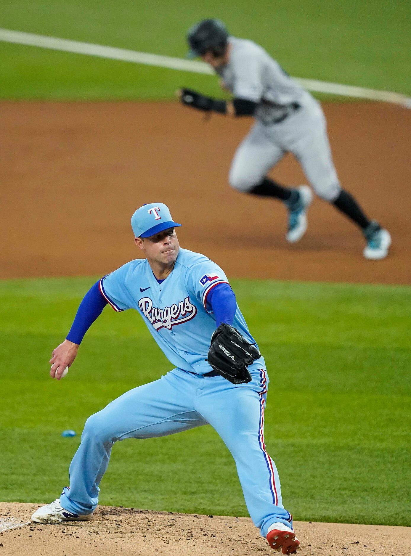 Texas Rangers pitcher Corey Kluber pitches as Colorado Rockies shortstop Trevor Story takes...