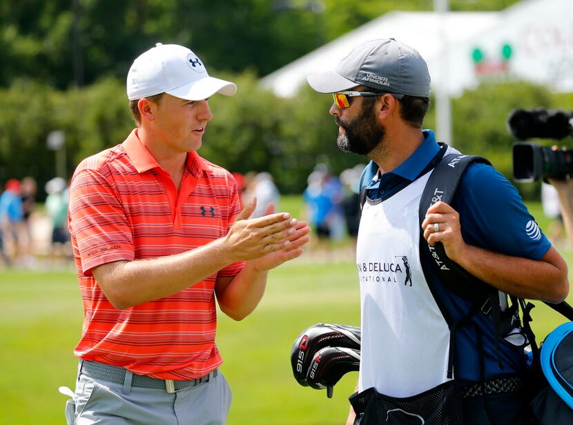 Golfer Jordan Spieth (left) converses with his caddie Michael Greller following his first...