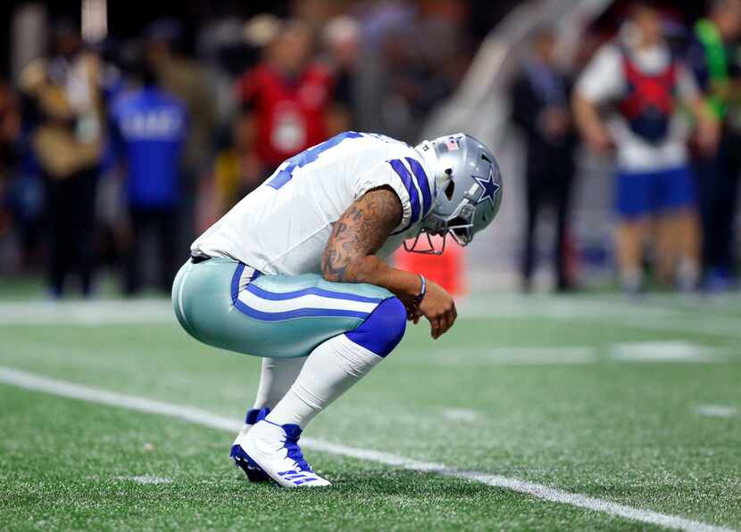 FILE - Cowboys quarterback Dak Prescott (4) stretches his back after taking a hit in the...