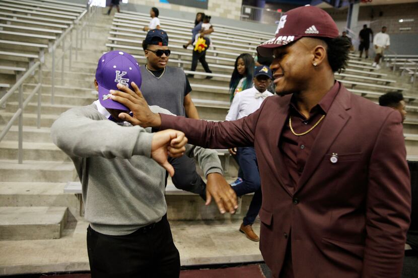 Devodrick Johnson from Kimball High School signing for Texas A&M (right) pushes the hat of...
