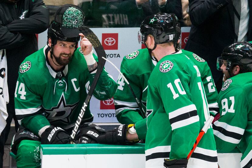 Dallas Stars left wing Jamie Benn (14) puts on a hat thrown on the ice by a fan after he...