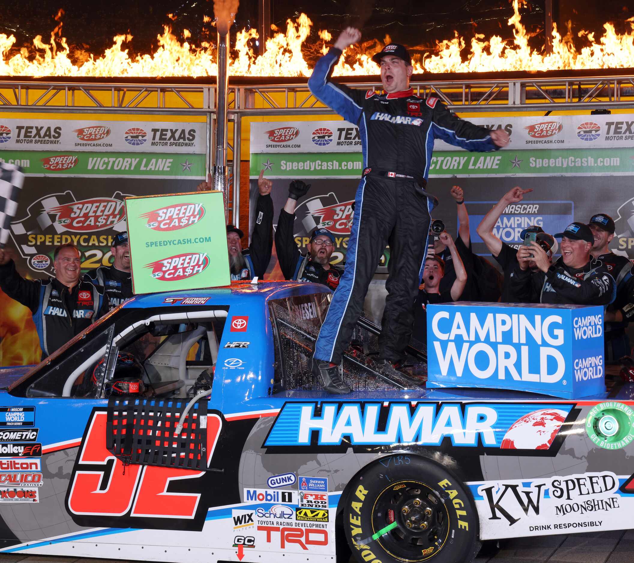 Driver Stewart Friesen lets out a yell as he celebrates with his race crew from atop his #52...