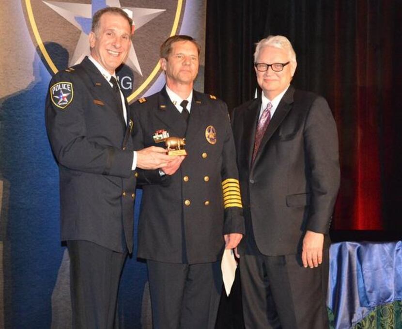 Capt. John Thorpe, center, receives the Brass Pig Award from Chief Larry Boyd, left, and...