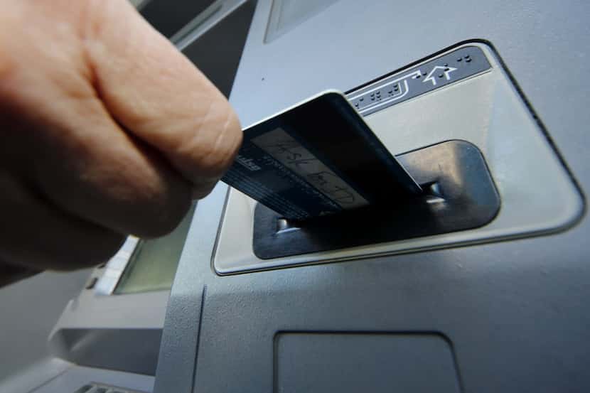 A person inserts a debit card into an ATM machine.