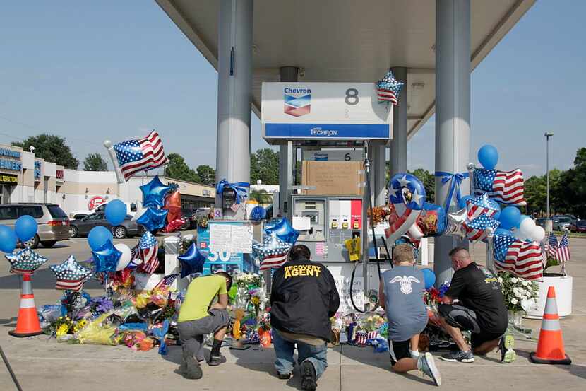 Mourners gather Saturday at a gas station in Houston to pay their respects at a makeshift...