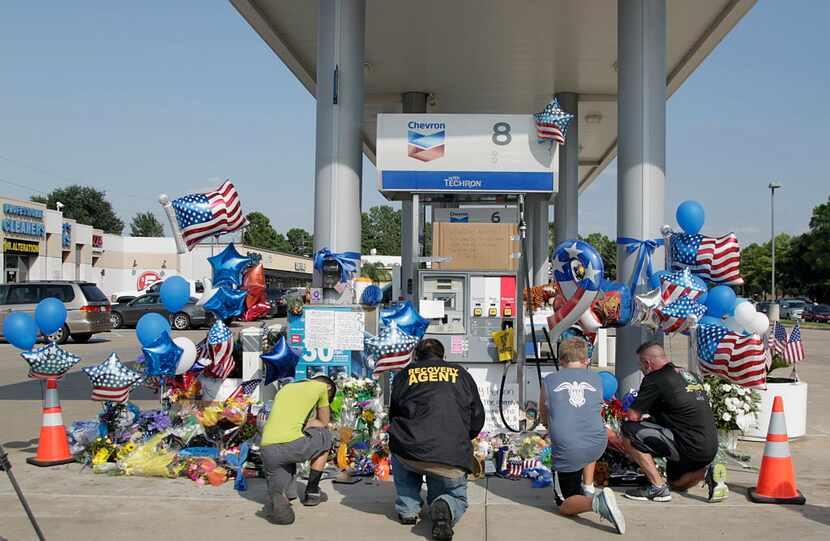 Mourners gather Saturday at a gas station in Houston to pay their respects at a makeshift...