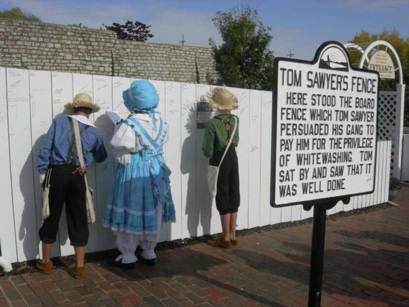 Children dressed as Tom Sawyer and Becky Thatcher signing the famous white picket fence in...