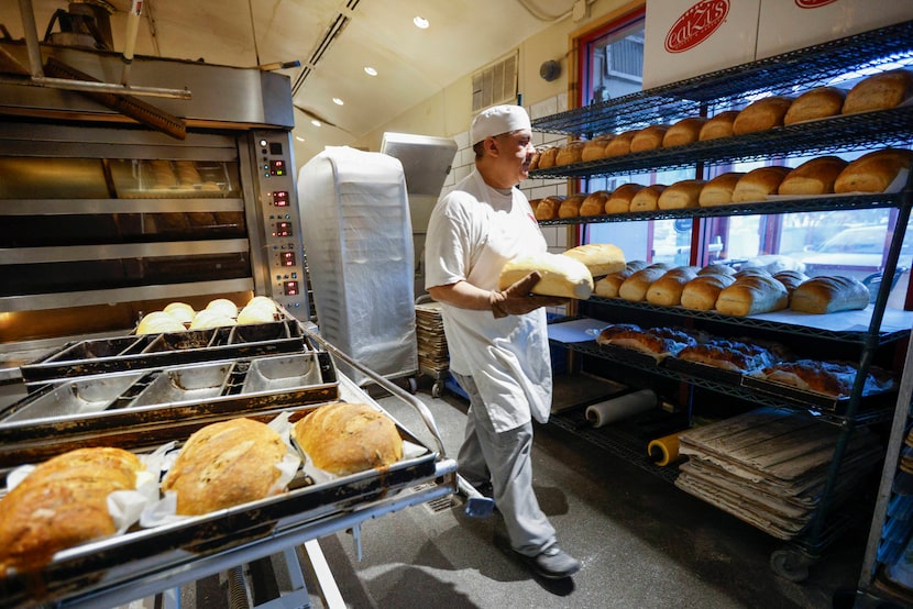 Baker Andres Ayala takes bread out of the oven and places it onto a shelf at the original...