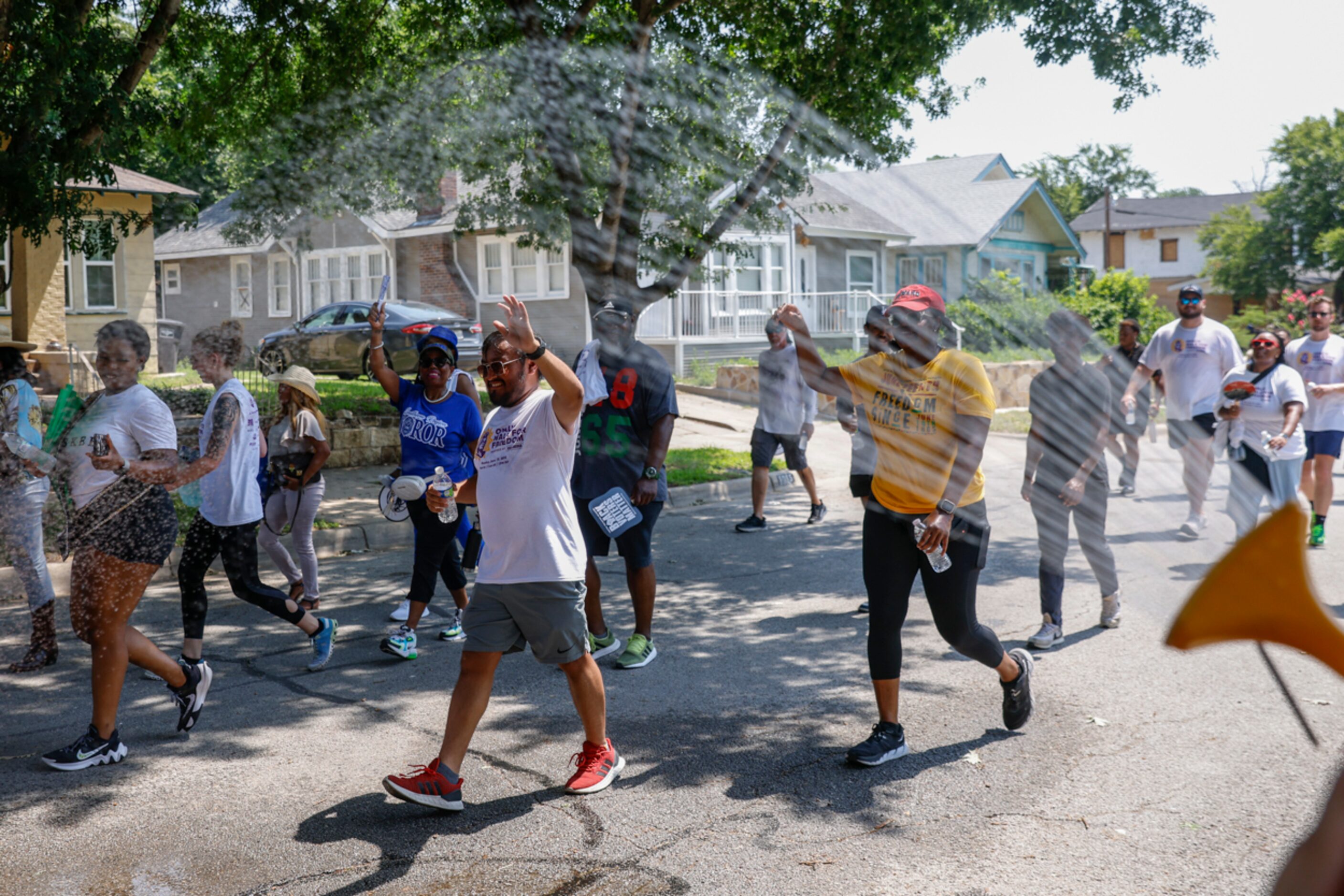 Crowd cools off as they walk by hose water during Opal's Walk for Freedom on Monday, June...